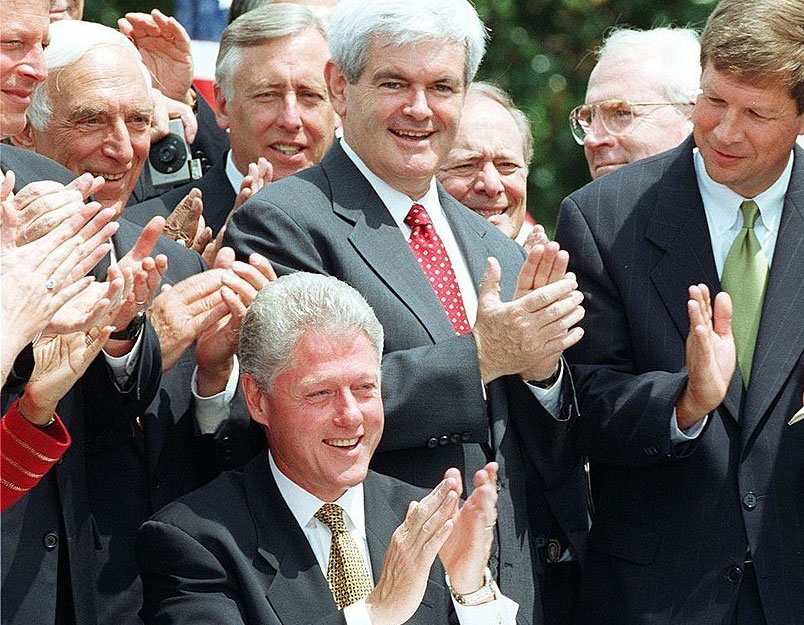 US House Majority Leader Newt Gingrich (stands behind Clinton) applauds US President Bill Clinton after Clinton signed the Balanced Budget Agreement on the South Lawn of the White House August 5th in Washington.