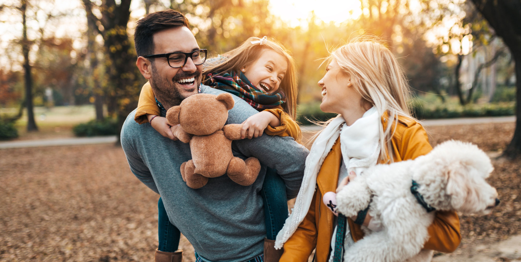 Young daughter with her mother, father and dog, enjoying together in park.