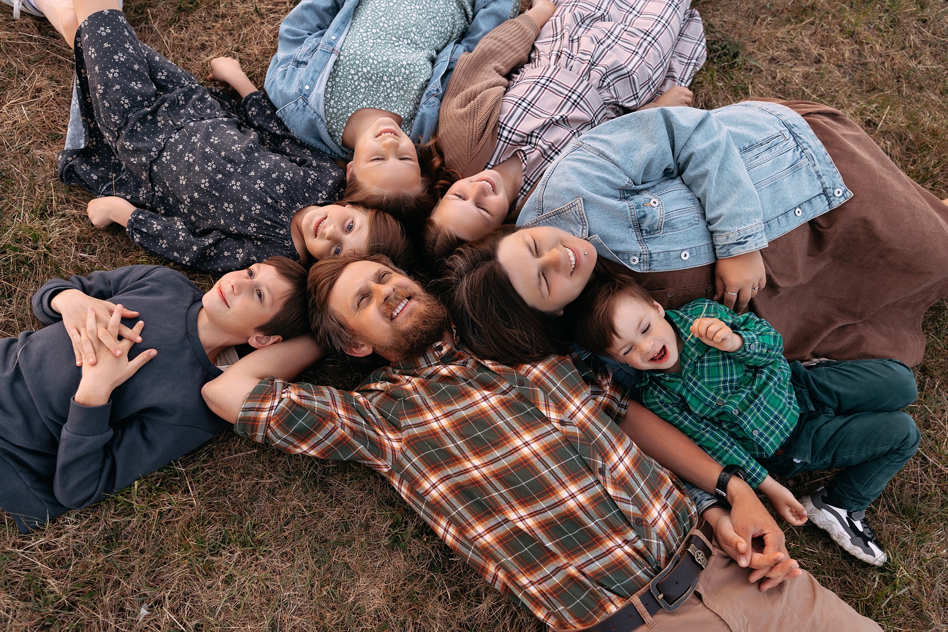 A large happy family laying head-to-head in a field.