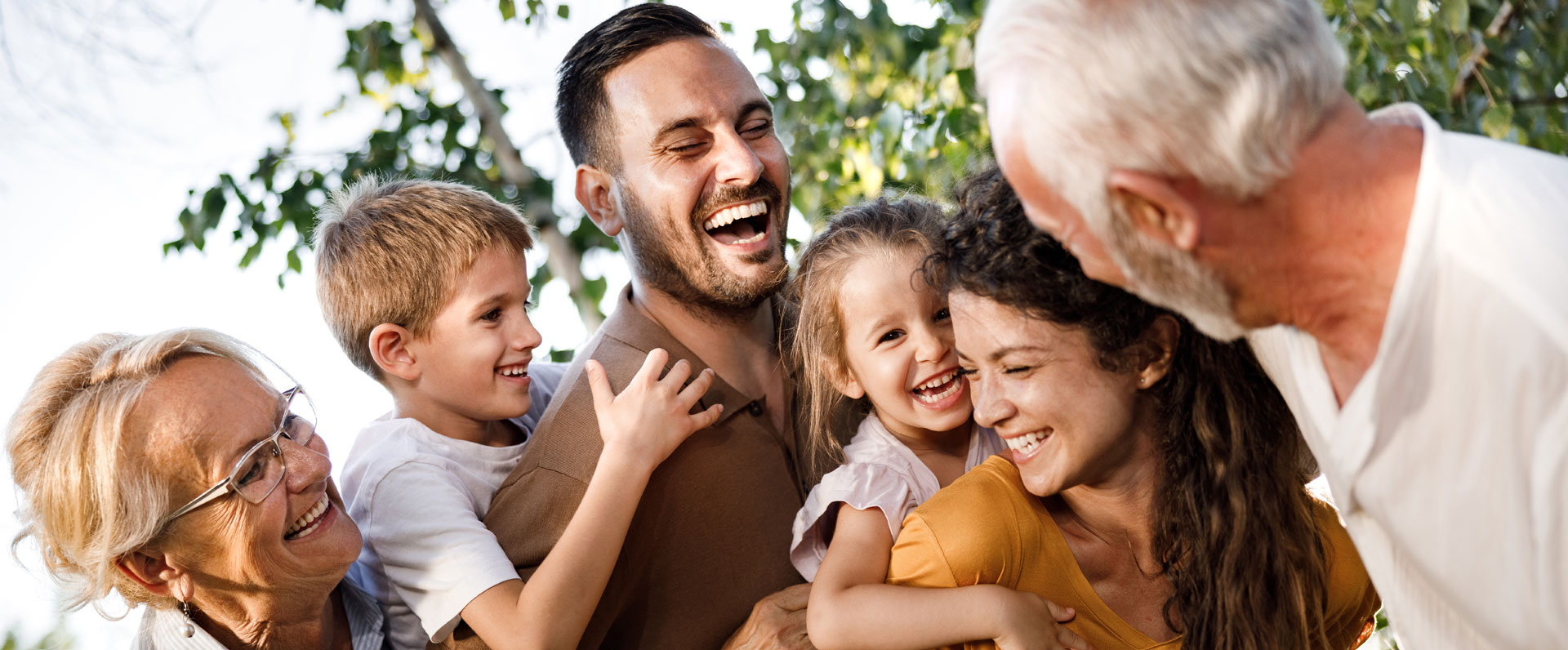  A happy multigenerational family hugging and having fun outside.