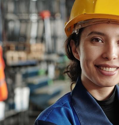Young woman with hard hat standing proud at workplace.