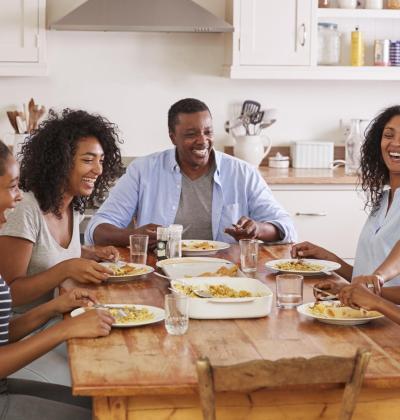 Family With 3 Teenage Children Eating Meal In Kitchen.