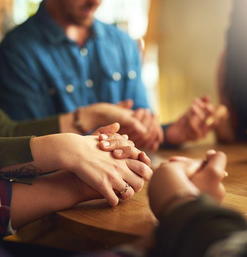 Hands holding each other during prayer.