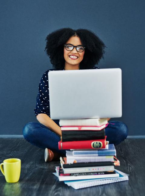 Woman smiling and using laptop while sitting.