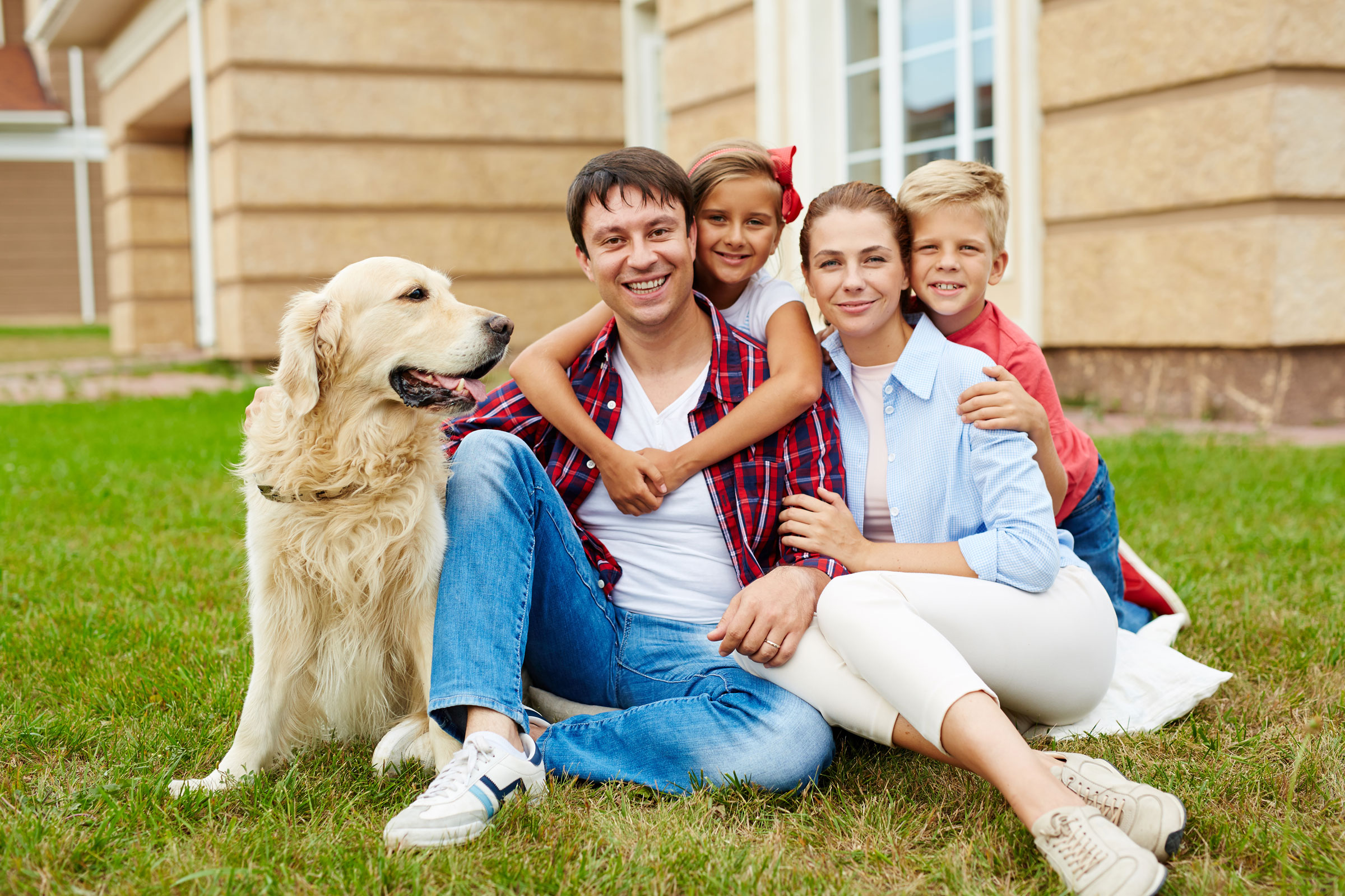 Mother and father sitting with their daughter, son, and a dog in their yard.